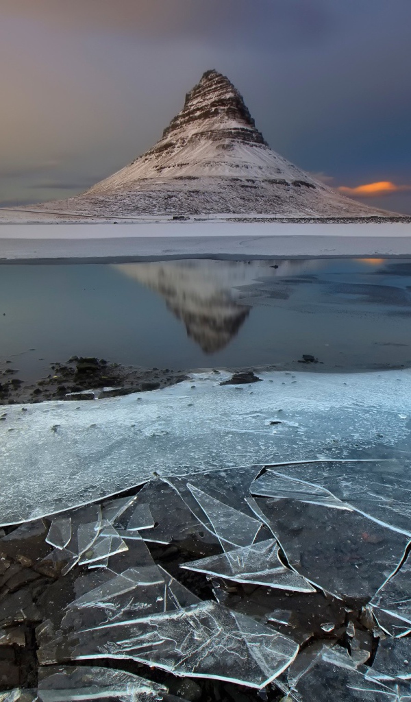 Тонкий лед озера на фоне горы