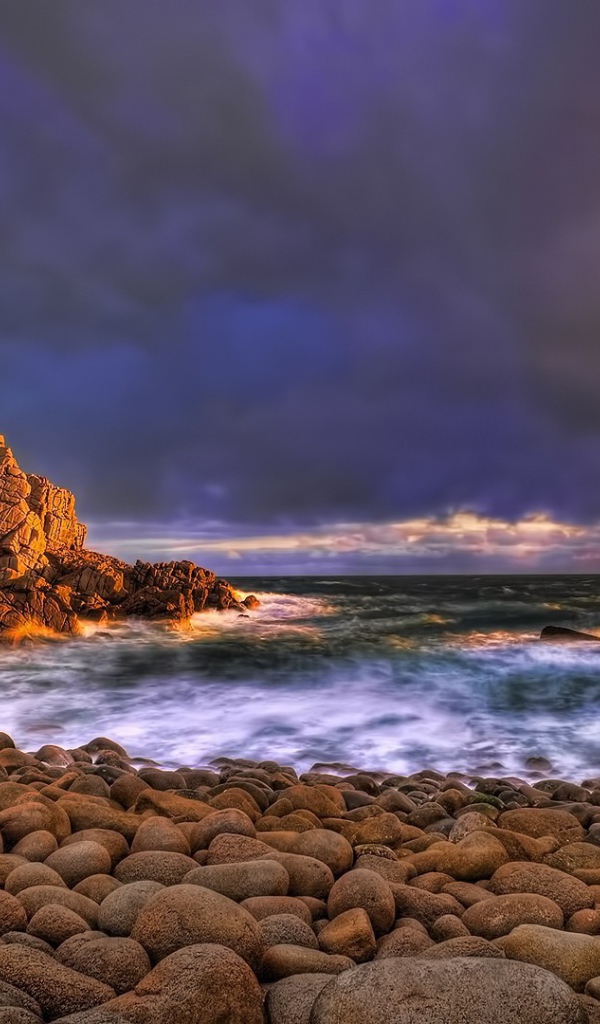 Большие гладкие камни на берегу бурного моря