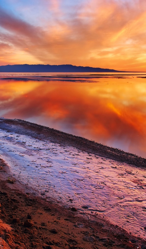 Оранжевые облака отражаются в зеркальной глади воды