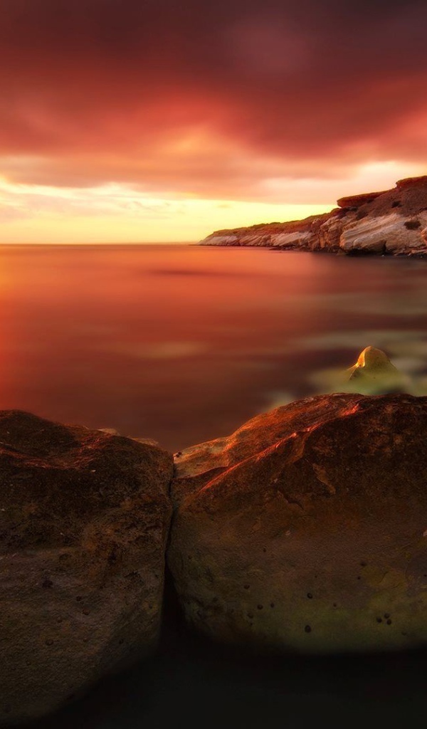 Два больших камня на берегу моря на закате