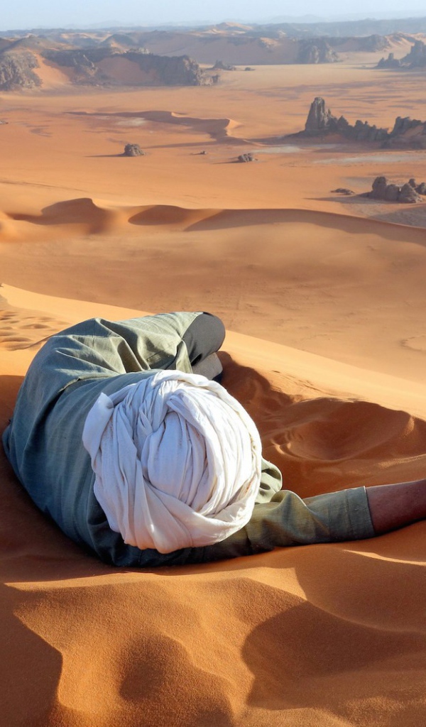 Человек лежит на песке в пустыне