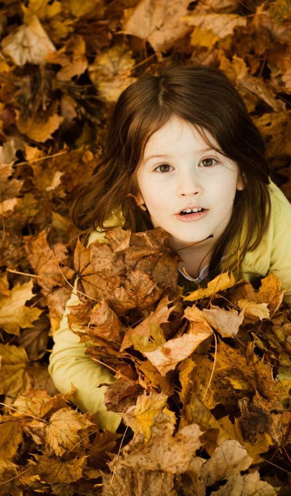 Девочка зарылась в опавшие листья