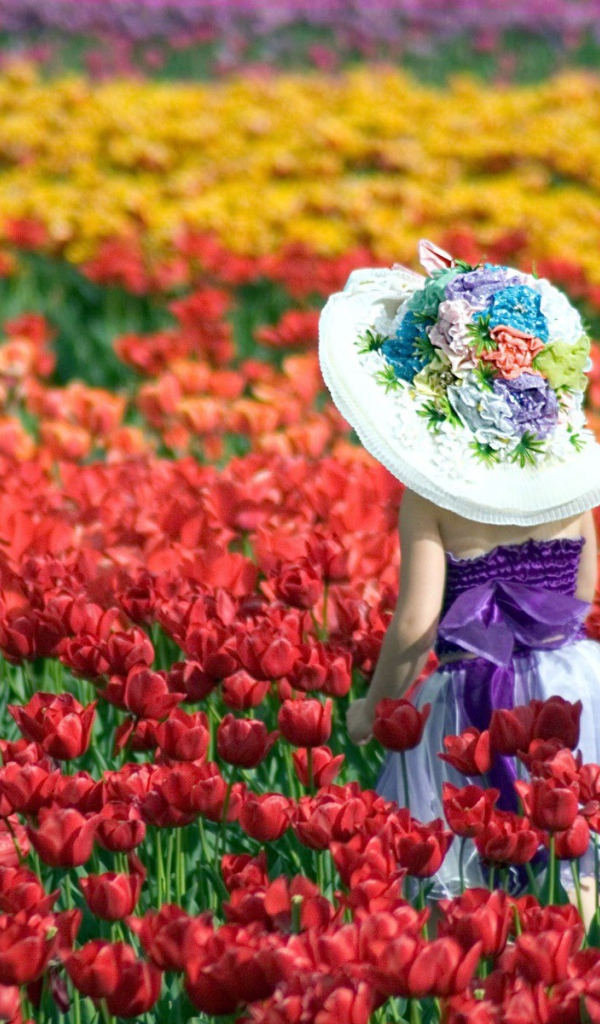 Девочка в шляпе идет среди красных тюльпанов