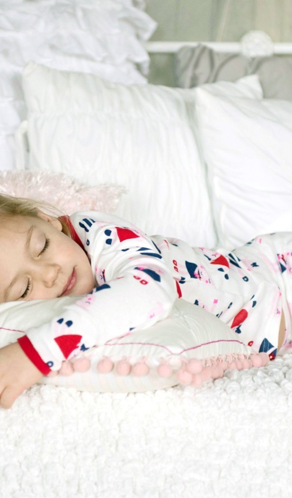 Девочка в пижаме спит на кровати