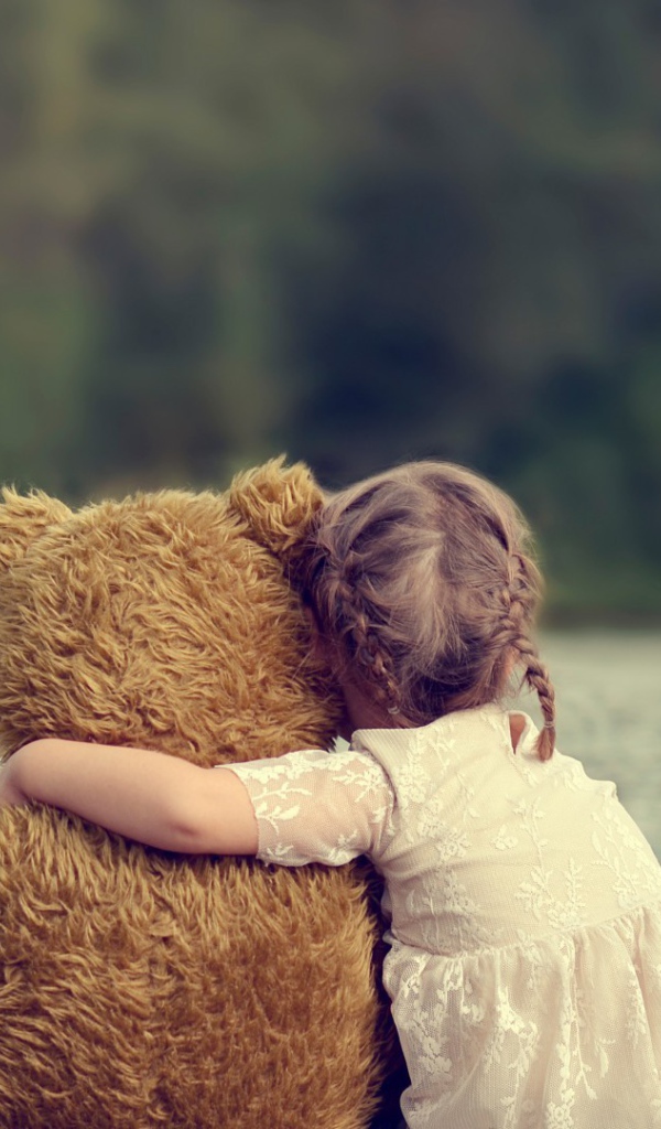 Девочка сидит в обнимку с плюшевым медведем