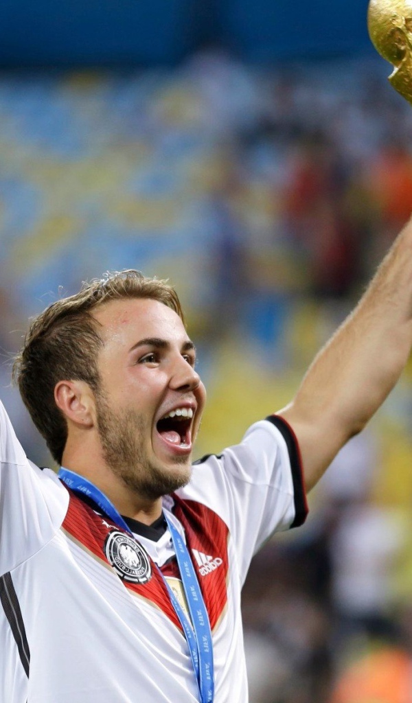 Немецкий футболист Марио Гётце держит в руке кубок