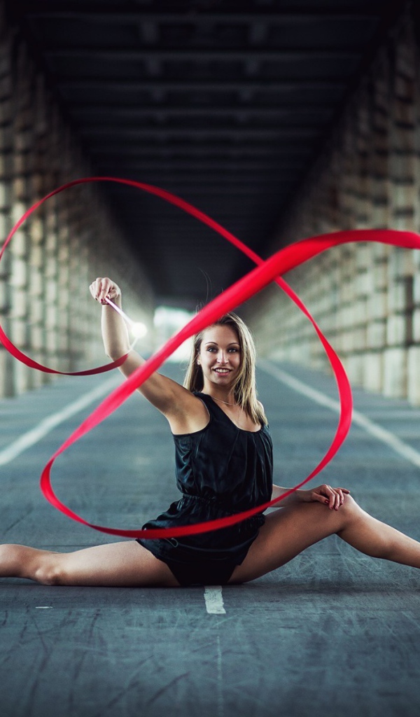 Гимнастка упражняется с красной лентой