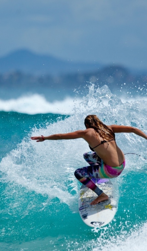 Девушка серфер оседлала голубую волну