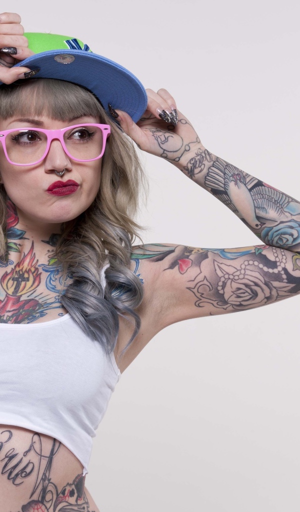 Tattooed woman in a cap and pink glasses