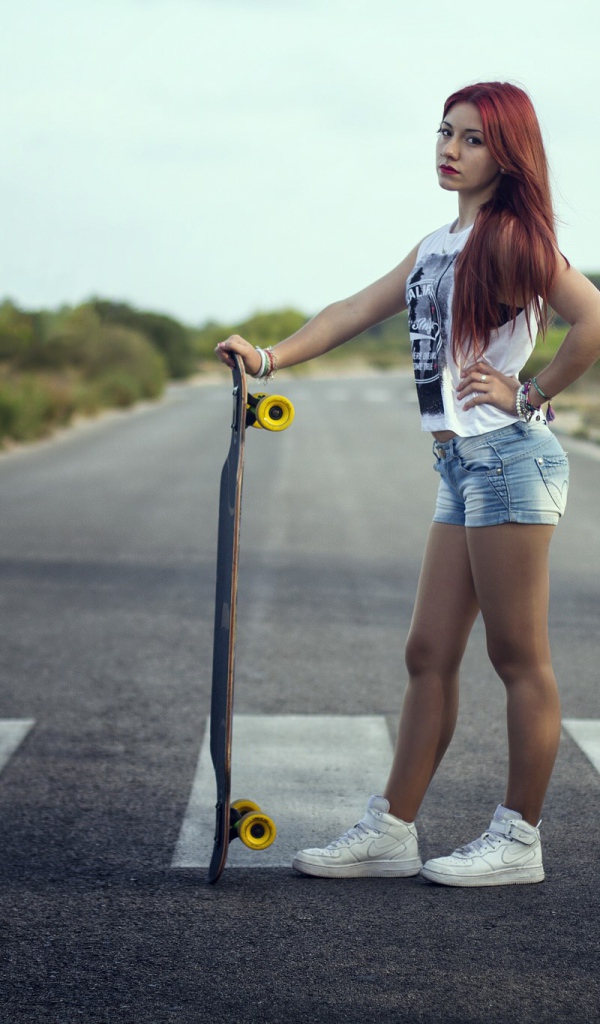 Девушка со скейтбордом стоит на переходе