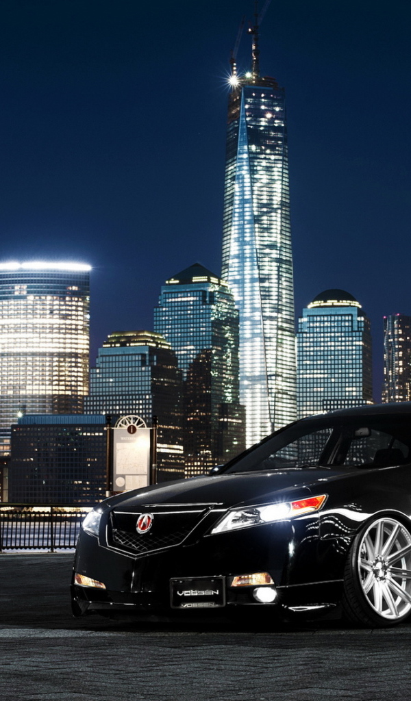 Black car Acura TL on a background of night skyscrapers