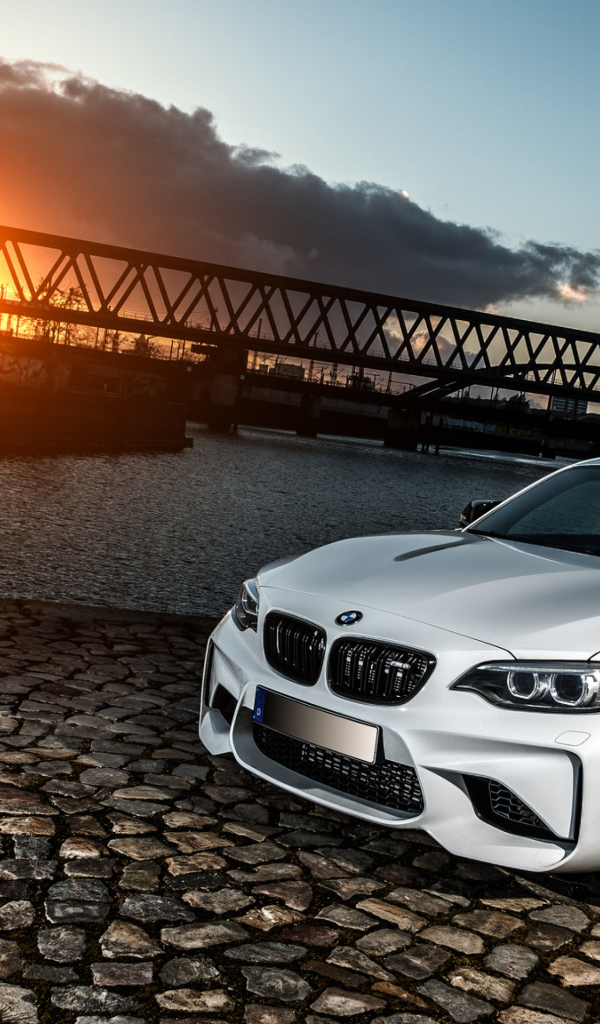Белый автомобиль BMW M2 на фоне заката 
