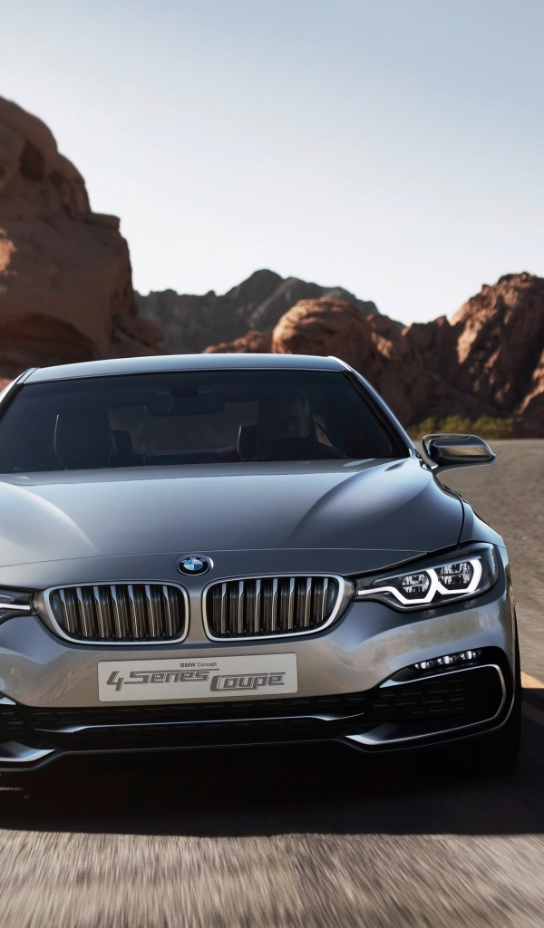 Серебристый автомобиль BMW 4 Series Coupe на дороге у скал