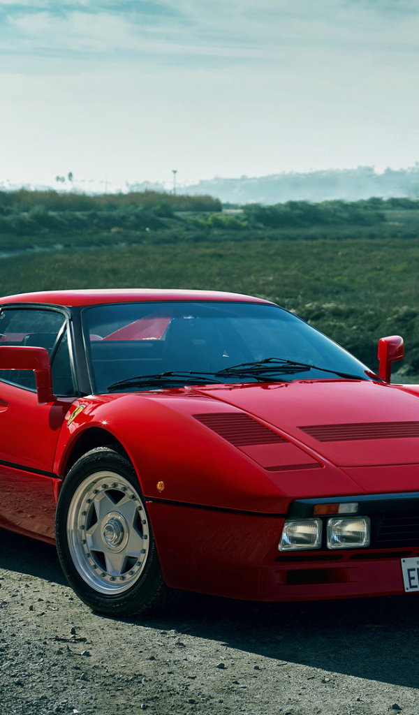 Красный быстрый автомобиль Ferrari 288 GTO у реки