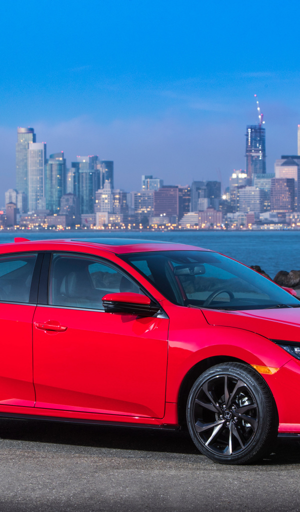 Red car Honda Civic Touring Hatchback, 2017 against the background of the city