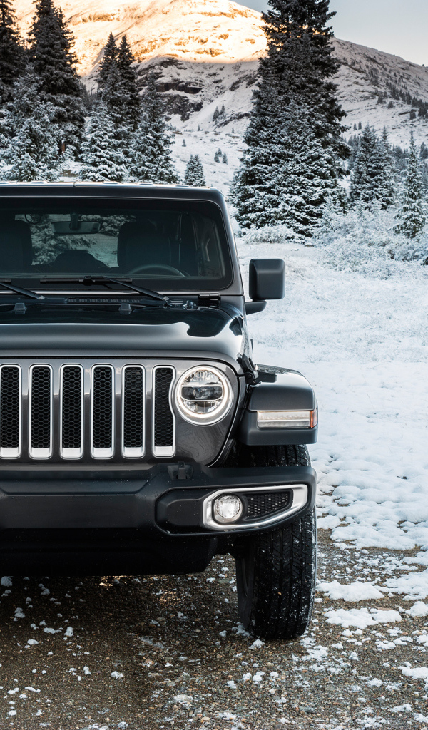 Внедорожник Jeep Wrangler Unlimited Sahara, 2018 на заснеженной дороге на фоне гор