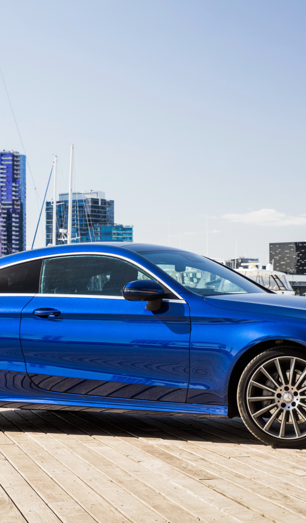 Синий автомобиль Mercedes-Benz C205 на фоне города