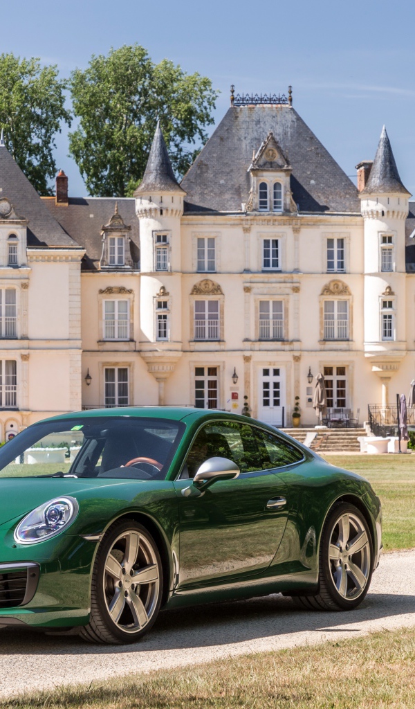 Зеленый спортивный автомобиль Porsche 911 Carrera на фоне дома