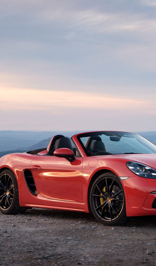 Красный автомобиль кабриолет Porsche 718 Boxster на фоне горизонта 