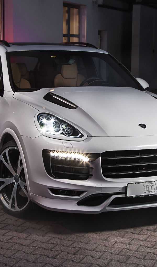 Белый внедорожник Porsche Cayenne с включенными фарами