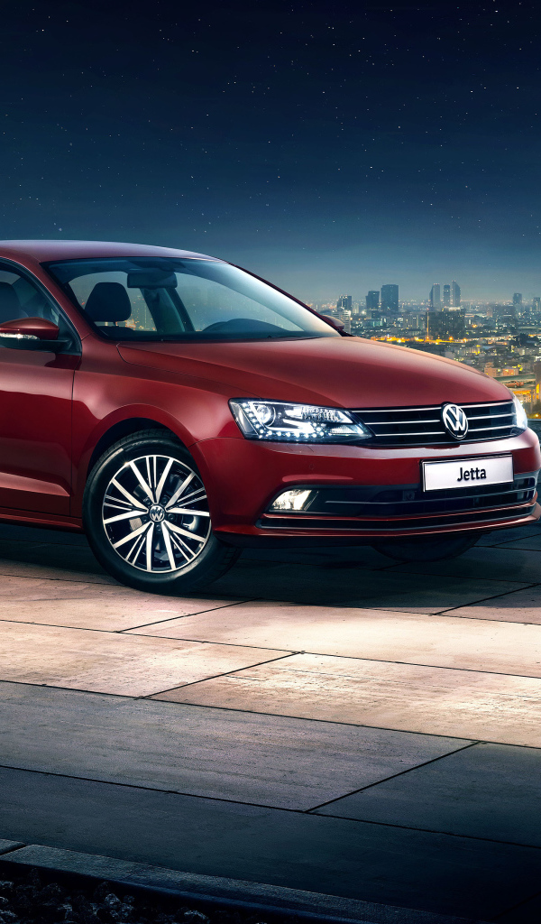 Красный автомобиль Volkswagen Jetta на фоне ночного города
