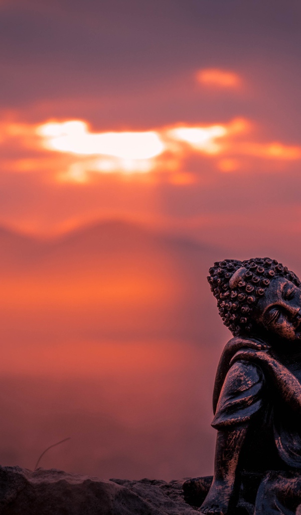 Статуя Будды на фоне солнца на закате