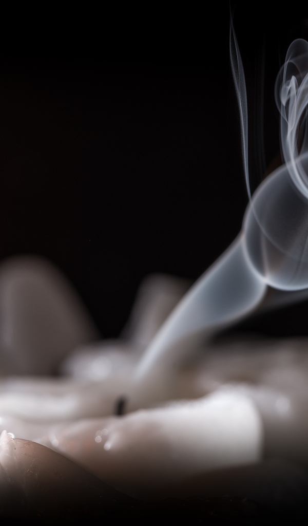 Огонь горящей свечи с дымом на черном фоне