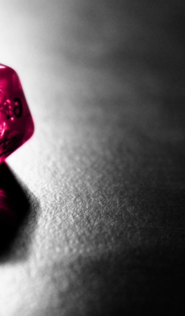 Розовый фигурный кубик отражается серой поверхности стола