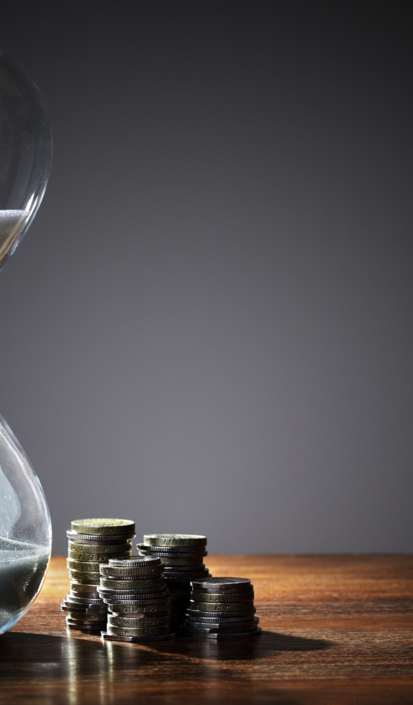 Монеты и песочные часы на столе