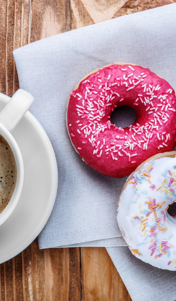 Чашка кофе с тремя аппетитными пончиками на столе