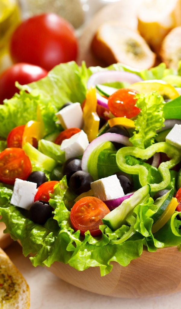 Аппетитный Греческий салат на тарелке с листьями салата