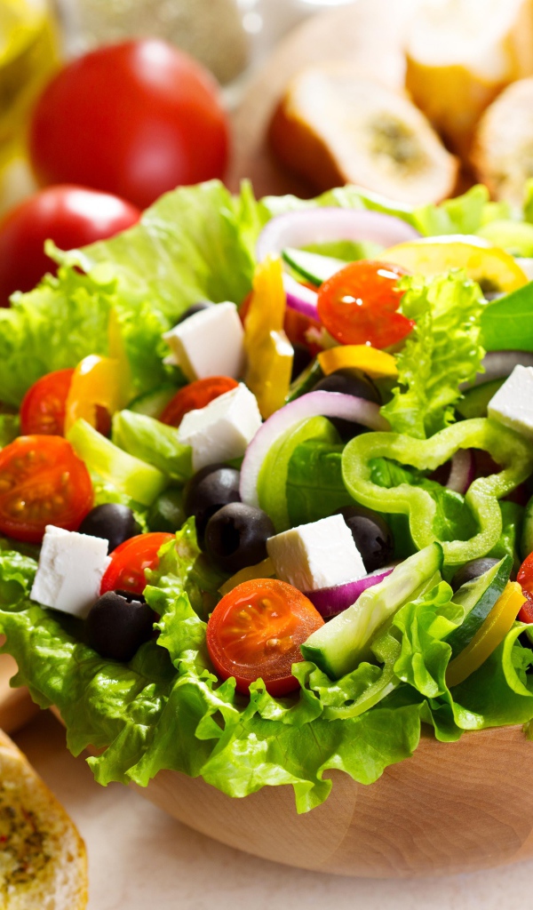 Аппетитный Греческий салат на тарелке с листьями салата
