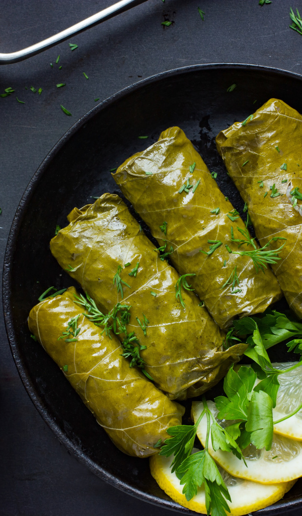 Аппетитная долма с кусочками лимона на столе 