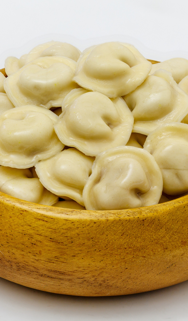 Аппетитные пельмени в деревянной миске на сером фоне