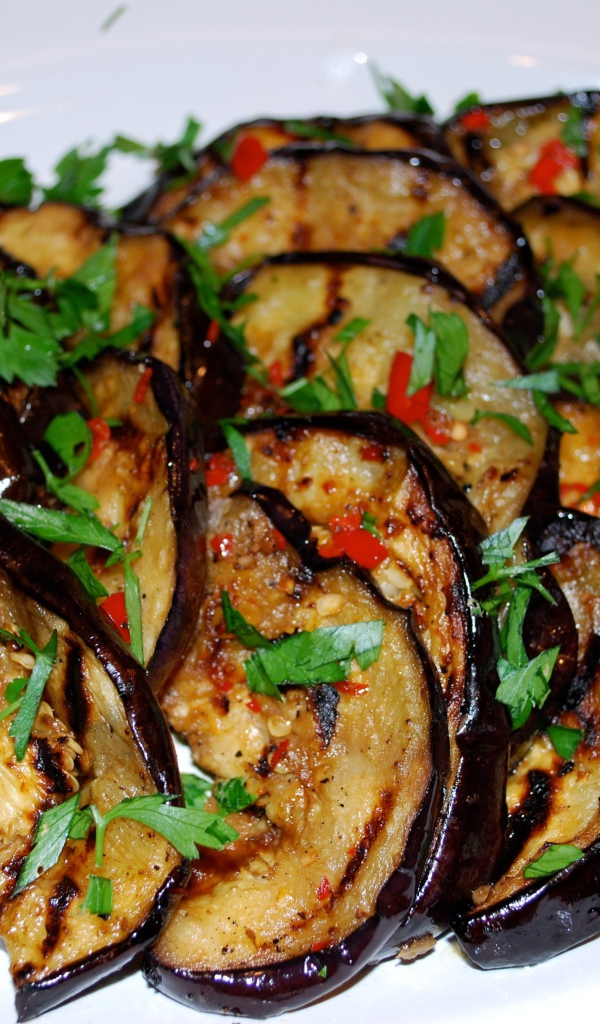 Аппетитные жареные баклажаны на тарелке с зеленью