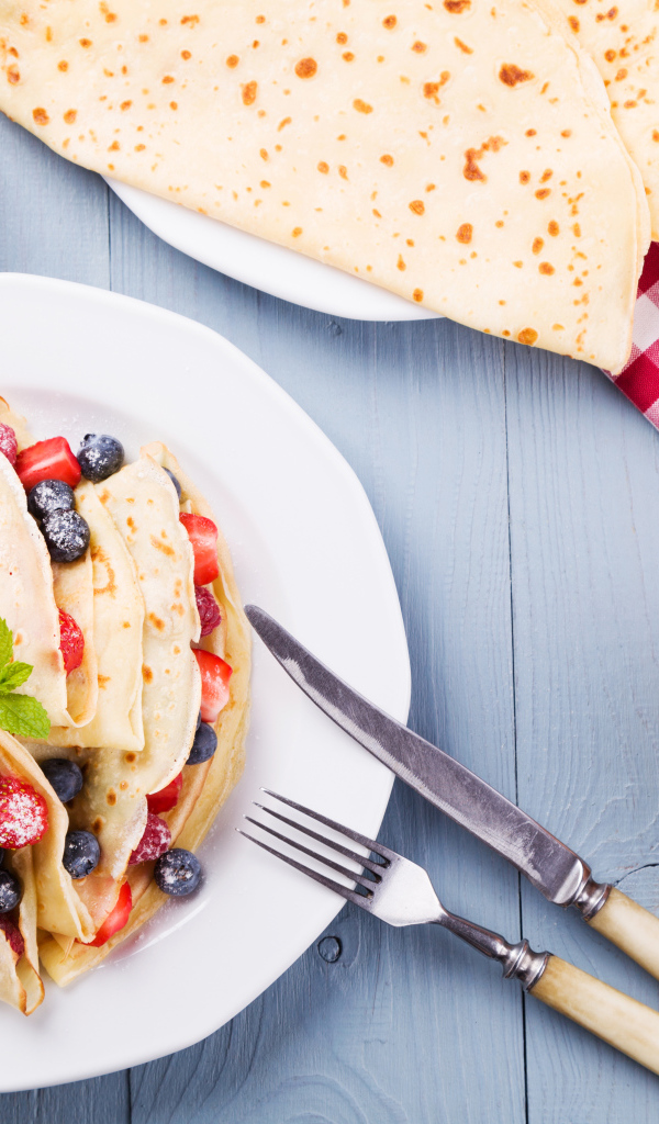 Аппетитные блинчики с ягодами на белой тарелке 