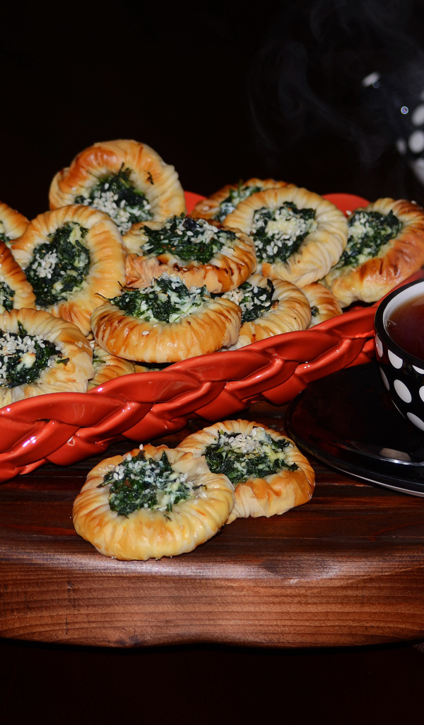 Булочки с зеленью и горячим чаем на черном фоне