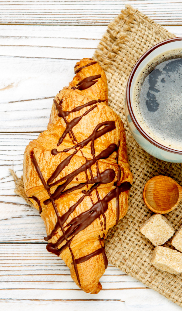 Круассан с шоколадом и чашкой кофе на столе