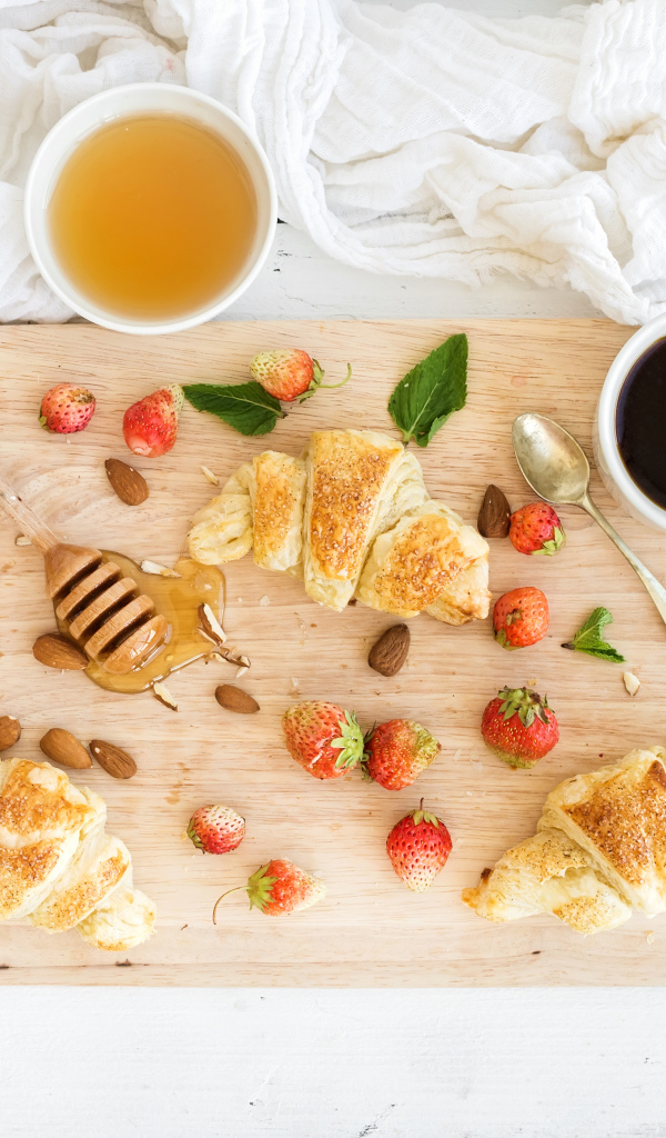 Круассаны, мед, свежие ягоды клубники и кофе на завтрак