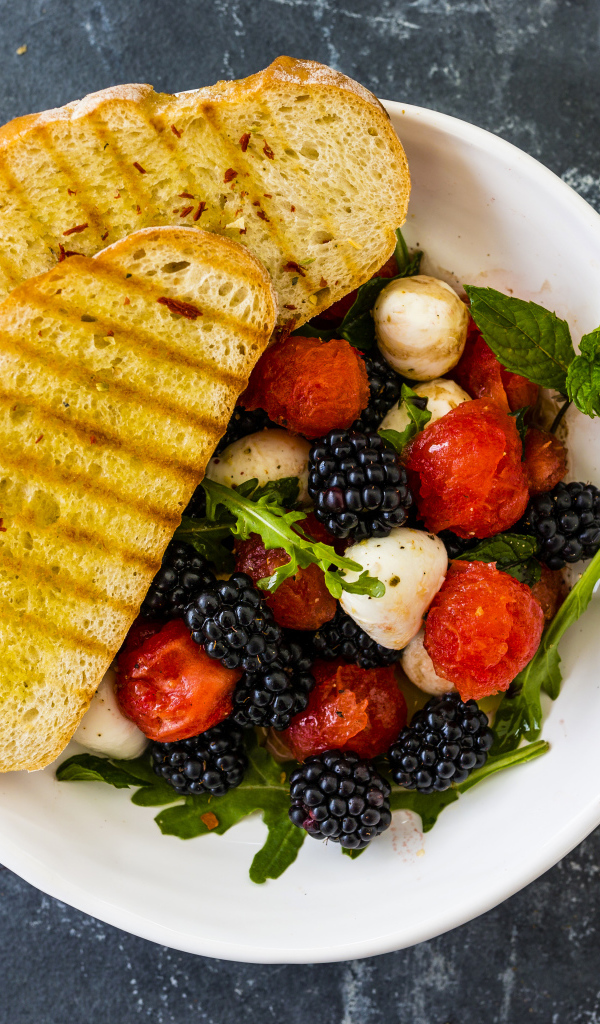 Гренки с салатом из ягод на белой тарелке