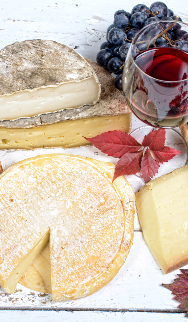 Дорогой сыр с плесенью на столе с виноградом и красным вином