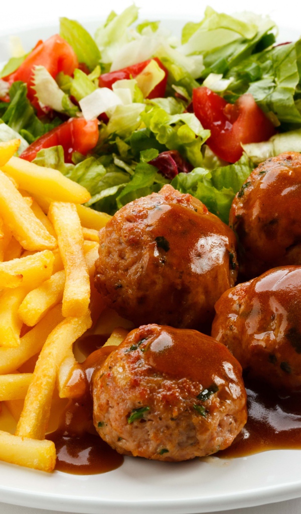 Картофель фри на белой тарелке с салатом и фрикадельками