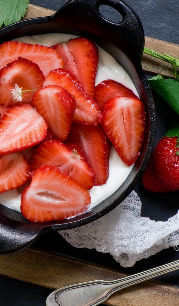 Свежая клубника с йогуртом на завтрак на столе с белым цветком