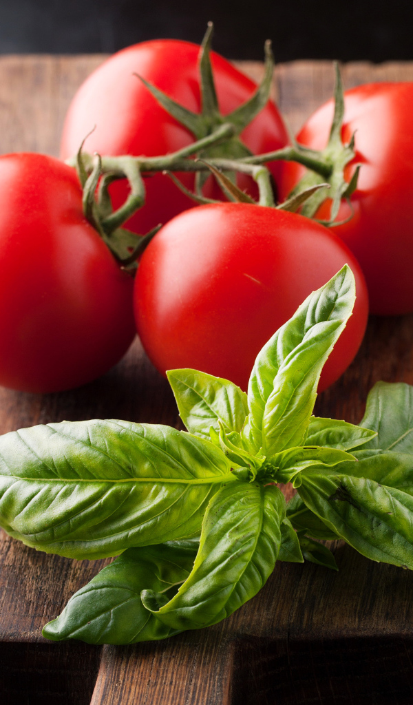 Свежие помидоры на разделочной с зеленью