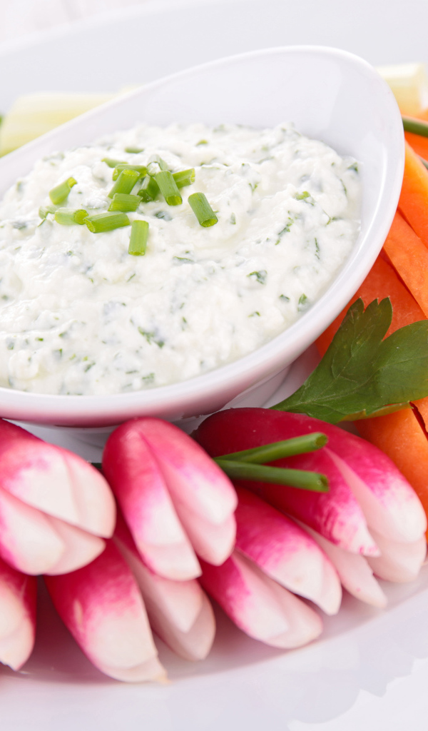 Свежие овощи с соусом в белой тарелке 