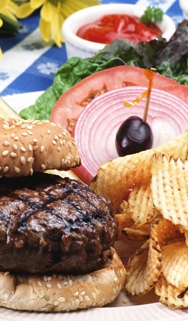 Гамбургер с котлетой и картофельные чипсы на тарелке с овощами