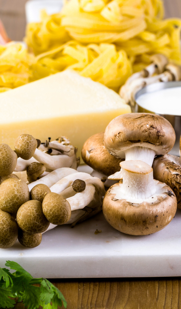 Грибы на разделочной доске с сыром, макаронами и зеленью