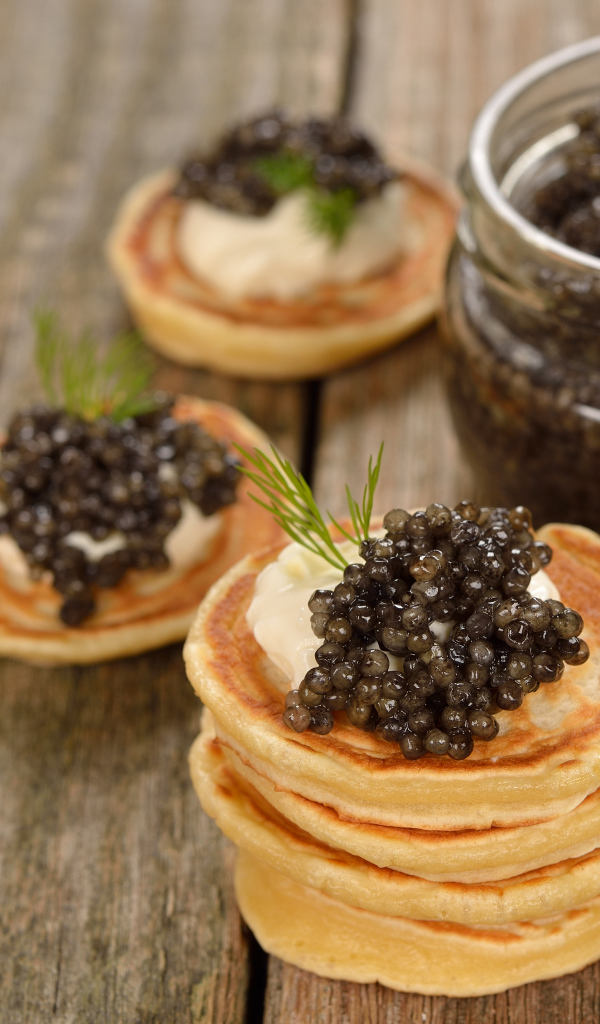 Оладьи с икрой и зеленью на столе