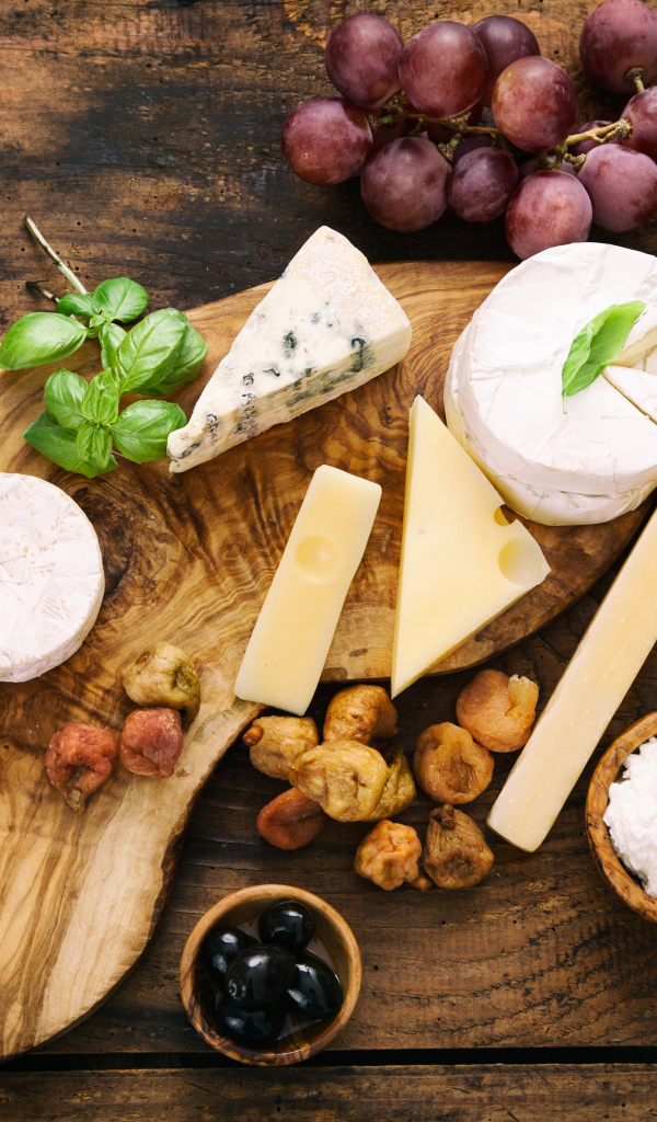 Кусочки сыра с виноградом и оливками на столе