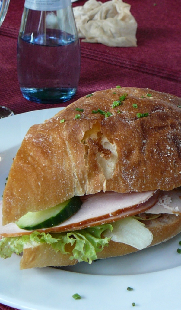 Сэндвич с ветчиной и овощами на столе в ресторане